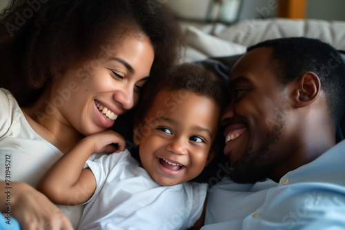 happy african american family laughing while lying on sofa at home

