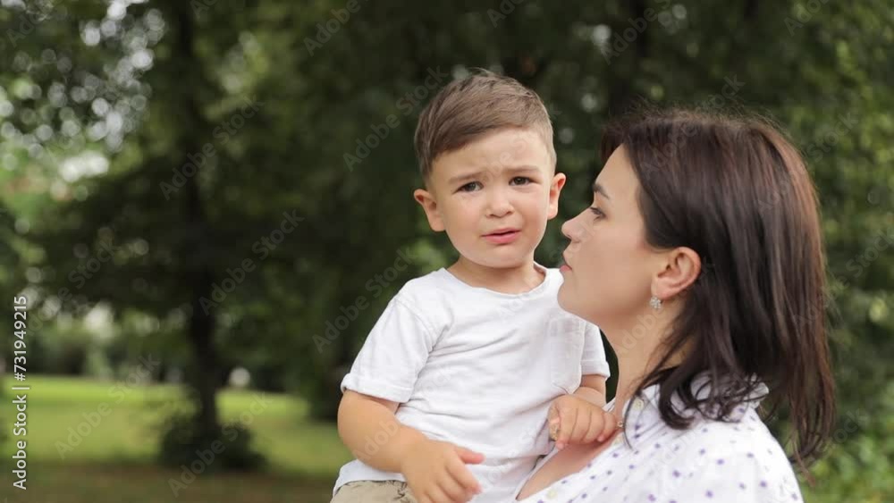 A woman is holding a little boy in her arms in a park A woman is holding a little boy in her arms in a park