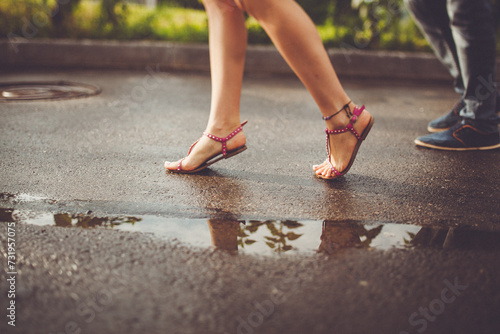 Couple walking on wet pavement  feet in sandals  flip-flops  and shoes.