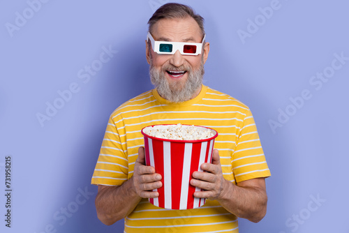 Portrait of impressed pensioner wear yellow t-shirt in 3d glasses hold popcorn staring at simulation isolated on violet color background