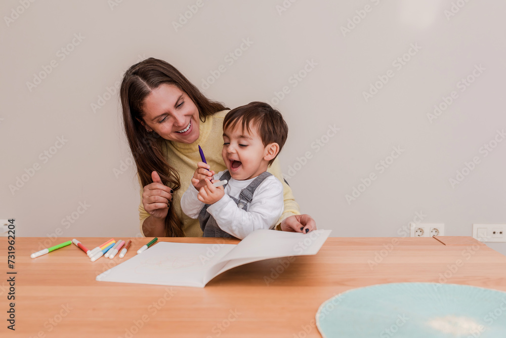 Delighted Toddler Boy and his happy mother having fun while Drawing with Marker at Home Delighted Toddler Boy and his happy mother having fun while Drawing with Marker at Home