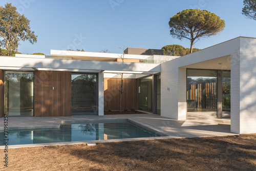Bilde på lerret White and wooden luxury house with private pool in a high-end urbanization seen