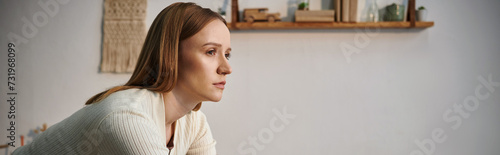 Fotografie young depressed grieving woman looking away in dark nursery room at home, horizo