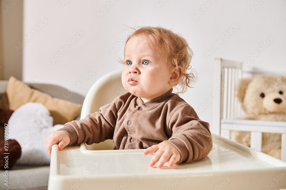 portrait of little toddler boy sitting in baby chair and looking away in nursery room at home portrait of little toddler boy sitting in baby chair and looking away in nursery room at home