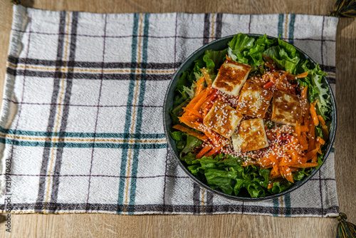 green salad with greek pan fried cheese served on wooden background with kitchen cloth textile napkin photo