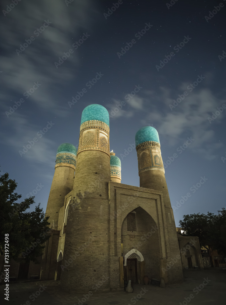 Night exterior of Chor Minor Madrasah in the ancient city of Bukhara in Uzbekistan, oriental architecture under the starry sky of a summer night