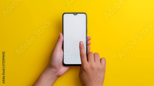 A hand is holding a smartphone with a blank screen against a vibrant yellow background, tapping the screen with one finger.