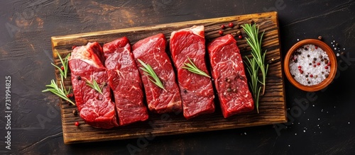 Top view of a cutting board with a variety of fresh raw beef steaks seasoned with spices.