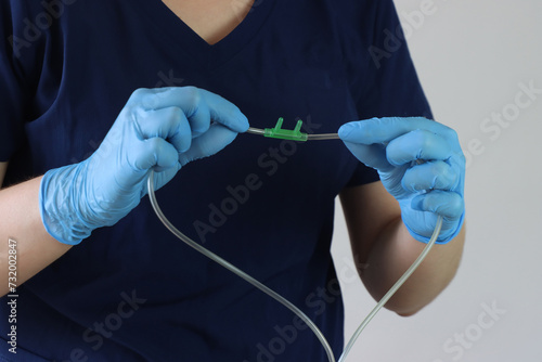 Professional wearing gloves holding a nasal cannula for oxygen delivery. Professional simulating holding the cannula to put in a patients face
