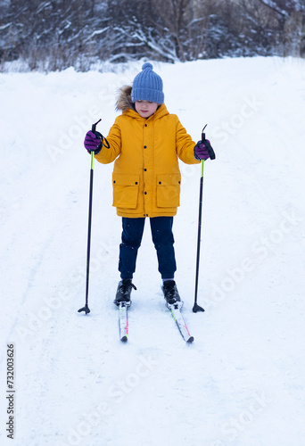 child boy in yellow clothes skiing in the snow on cold winter day outdoors