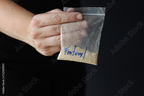 Woman holding a pack with fentanyl powder to illustrate the drug addiction 