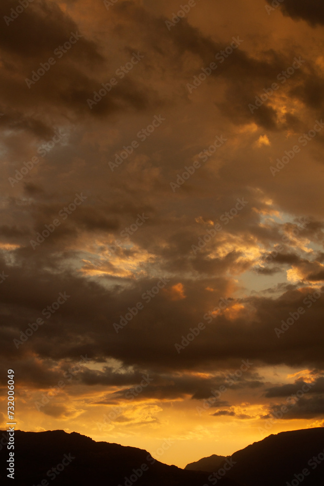 Cloudscape. Magical view of a dramatic sunset in the mountains. The beautiful sky, clouds and mountain dark silhouette with dusk colors.	
