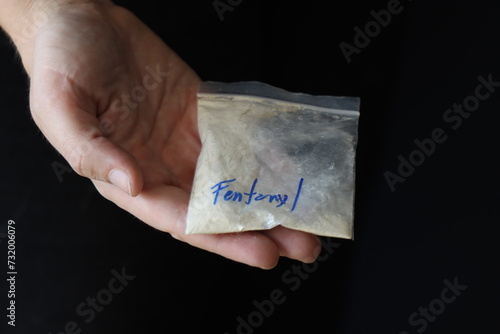 Woman holding a pack with fentanyl powder to illustrate the drug addiction 