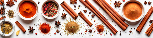 Top view of panorama with variety of aromatic spices such as cinnamon sticks, paprika, star anise, cumin, pepper and others over white table. Panoramic view of food background.