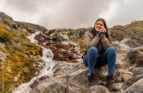 joven mujer sentada al lado de un riachuelo en la montaña © ASTRO