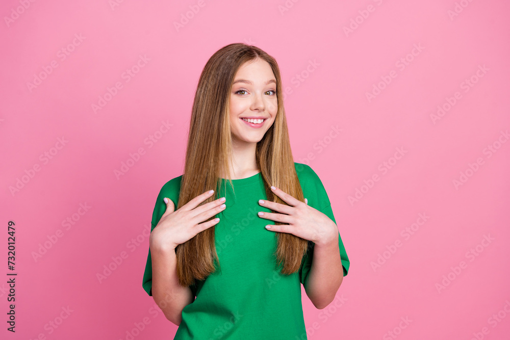 Portrait of youngster happy teenager blonde long hair girl in green t shirt touching her chest comfort isolated on pink color background Portrait of youngster happy teenager blonde long hair girl in green t shirt touching her chest comfort isolated on pink color background