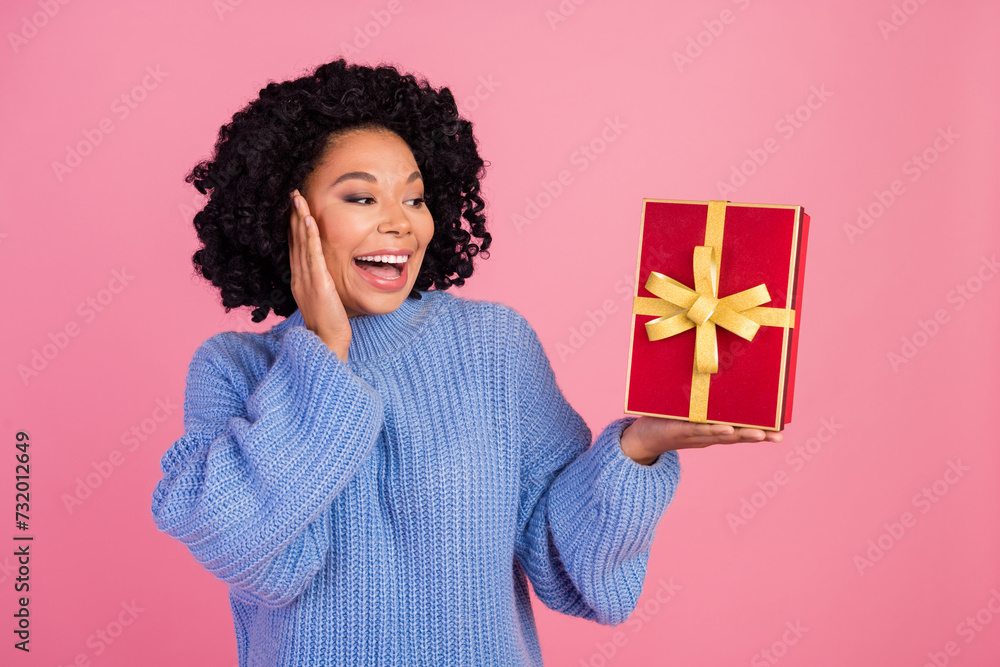 Photo portrait of attractive young woman hold look excited present dressed stylish blue knitted clothes isolated on pink color background Photo portrait of attractive young woman hold look excited present dressed stylish blue knitted clothes isolated on pink color background
