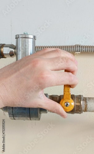 The locksmith's hand opening the acetylene supply valve on the gas pipe