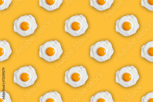 Seamless pattern of fried eggs on an yellow background. Directly above creative photo of fried eggs. 