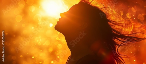 A woman, hair blowing in the wind, stands before a fiery landscape, creating a mesmerizing atmosphere with dancing flames.