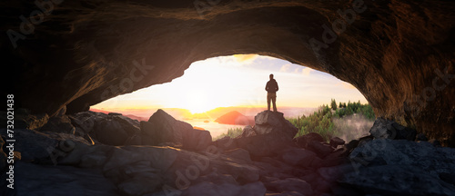 Adventure Man standing in rocky cave. Mountain Landscape with Ocean Coast in Background.