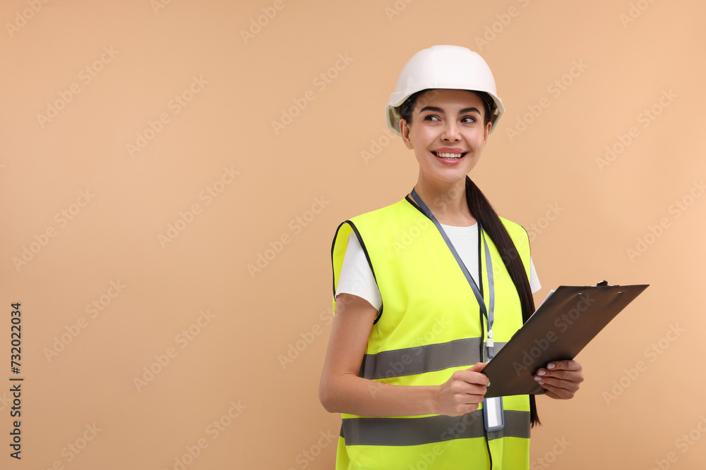 Engineer in hard hat holding clipboard on beige background, space for text Engineer in hard hat holding clipboard on beige background, space for text