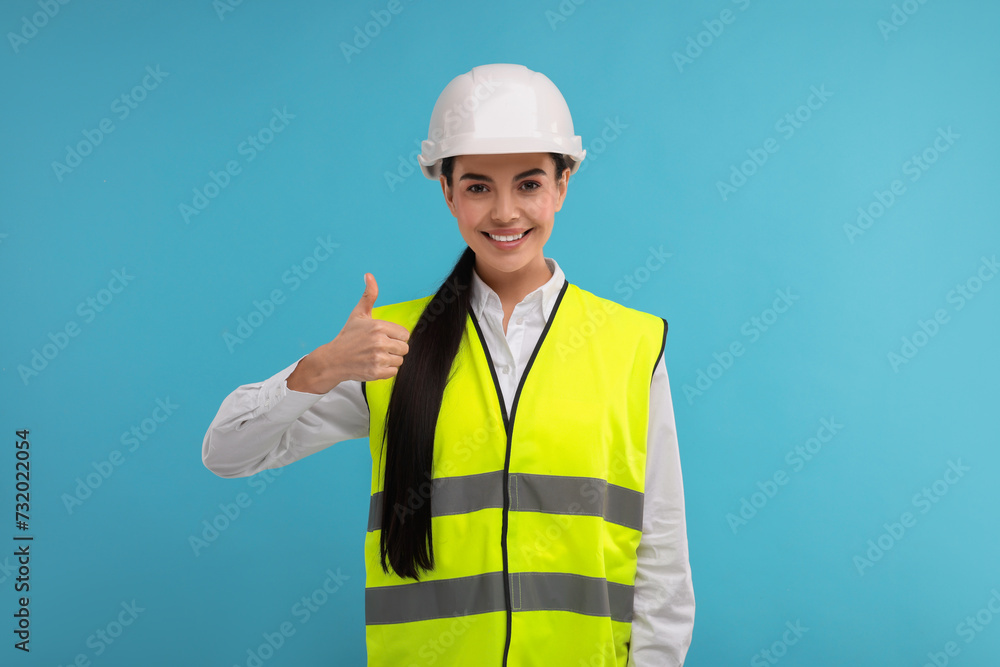 Engineer in hard hat showing thumb up on light blue background Engineer in hard hat showing thumb up on light blue background