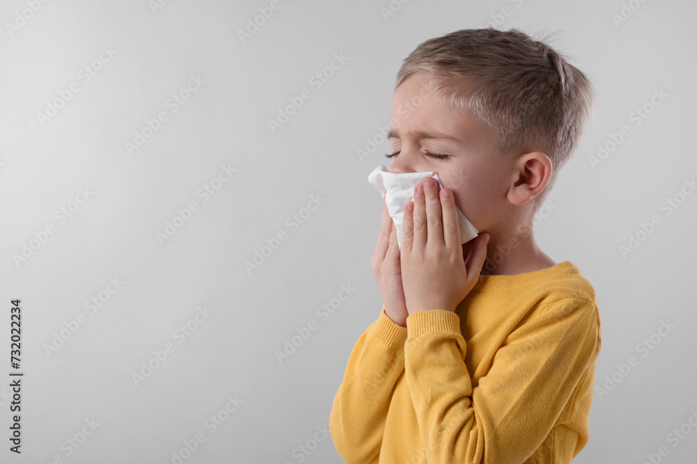 Sick boy with tissue coughing on gray background, space for text. Cold symptoms Sick boy with tissue coughing on gray background, space for text. Cold symptoms