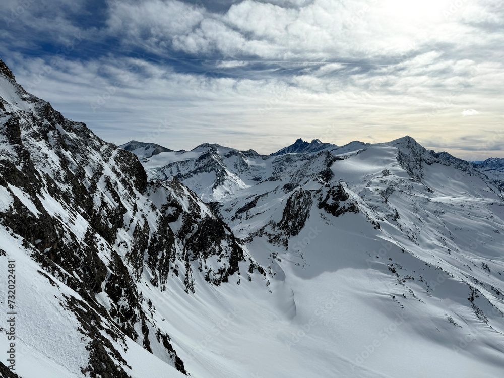 Fototapeta premium landscape of snow-covered mountains under a cloudy sky. The mountains are rugged and imposing, with sharp peaks and deep valleys filled with snow. snowy surfaces.