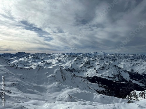 landscape of snow-covered mountains under a cloudy sky. The mountains are rugged and imposing, with sharp peaks and deep valleys filled with snow. snowy surfaces.