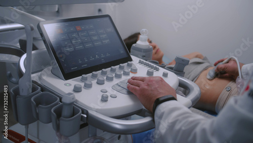 Close up of doctor using sonography machine with digital monitor. Medical specialist does ultrasound diagnostic to pregnant female patient. Modern clinic or medical center with advanced equipment. photo