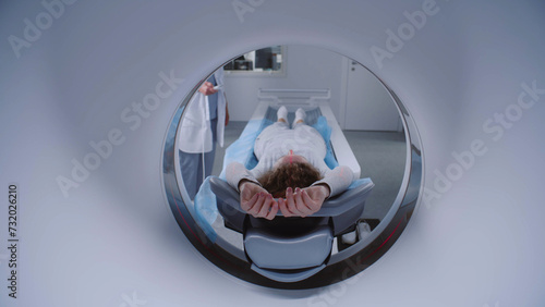 Close up shot of woman lying on CT or PET or MRI scan bed and moving inside machine. Scanning of patient body and brain using high-tech modern equipment. Medical facility with advanced technologies.