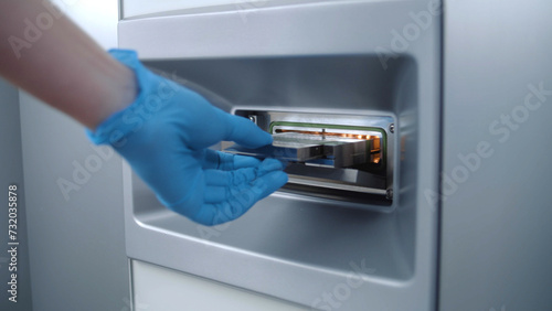 Scientist puts samples in microbiological analyzer in modern laboratory. Microbiologist does biotechnology or pharmaceutical research, studies cells and bacteria, develops vaccine in advanced lab.