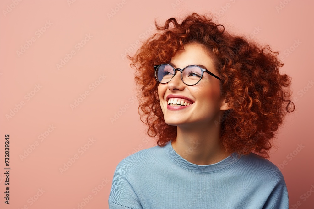 Half side portrait of happy smiling beautiful young redhead curly woman wearing glasses and blue sweater on pink background Half side portrait of happy smiling beautiful young redhead curly woman wearing glasses and blue sweater on pink background