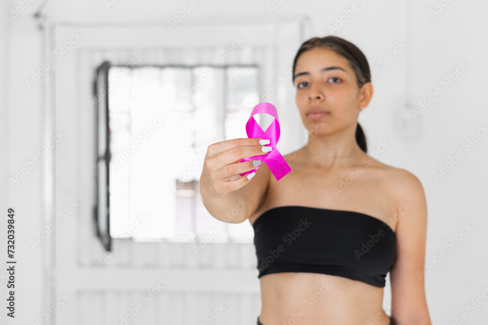 latina brunette woman showing a pink ribbon in her hand, symbol of the fight against cancer. latina brunette woman showing a pink ribbon in her hand, symbol of the fight against cancer.