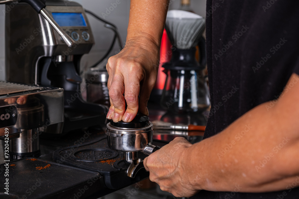 woman's hands pressing roasted and ground coffee to use in coffee maker woman's hands pressing roasted and ground coffee to use in coffee maker