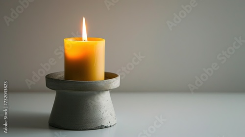 Stylish decor: Candle in a concrete candlestick on a white background. Modern design for ambient lighting