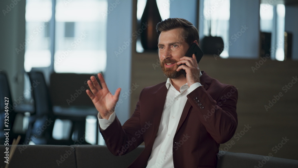 Cheerful businessman talking mobile phone in big office interior. Happy discuss Cheerful businessman talking mobile phone in big office interior. Happy discuss
