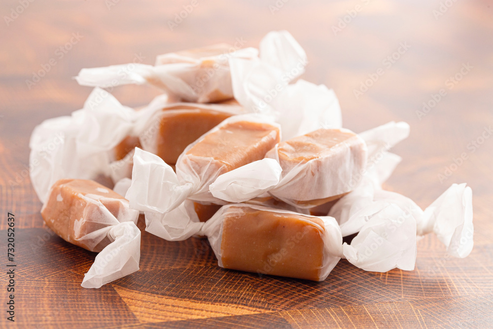 Hand Wrapped Soft Caramel Candies on a Wood Butcher Block Table Hand Wrapped Soft Caramel Candies on a Wood Butcher Block Table