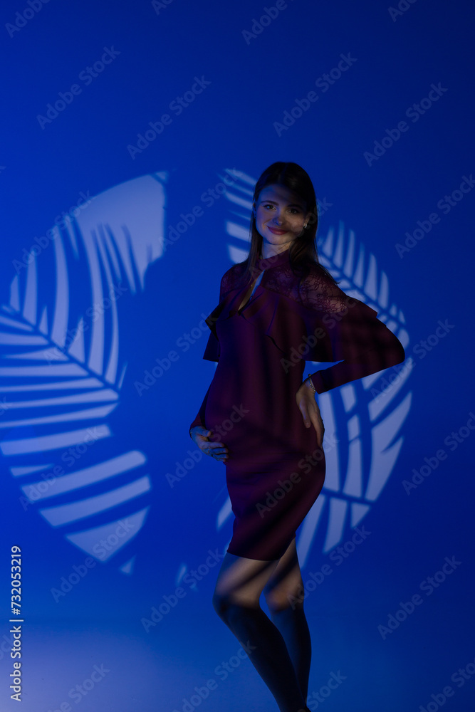 Obraz premium portrait of a pregnant woman on a blue background, studio pregnancy shoot, pregnant model posing in a studio