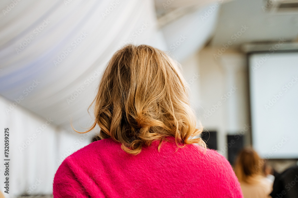 Naklejka premium Curly Blonde Woman Wearing Pink Jacket Sitting in Conference Room at Business Meeting