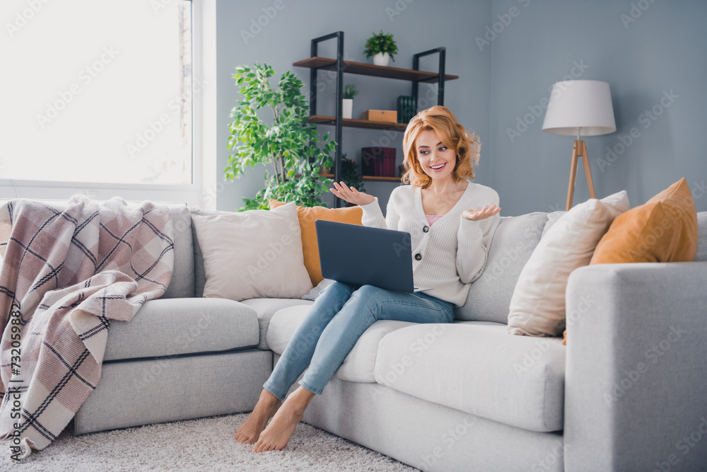 Full length portrait of cheerful gorgeous person sit sofa communicate video call netbook morning apartment indoors Full length portrait of cheerful gorgeous person sit sofa communicate video call netbook morning apartment indoors