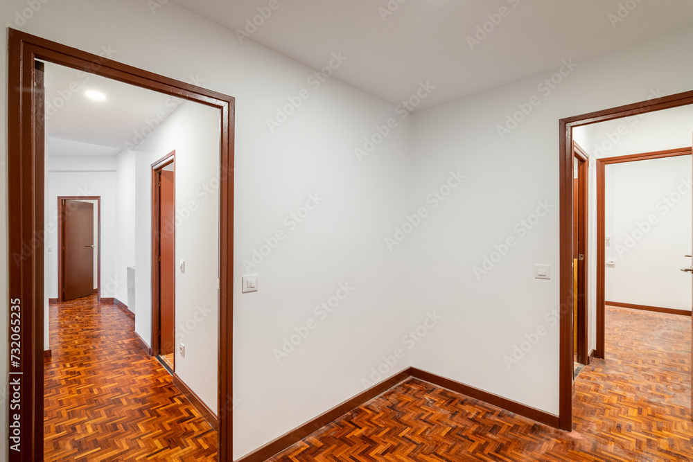 An apartment with corridor leading to empty rooms with wooden doors 