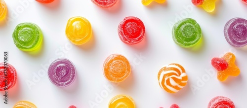A variety of colorful candies arranged in a circular pattern on a white surface create a visually appealing dish of sweetness.