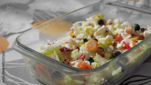 Delicious fresh nutritious healthy greek diet salad in a bowl on a sunny table, 4K smooth video of exotic spring appetizer with tomato, salad, carrot, apple, cranberry, cheese vegetables
