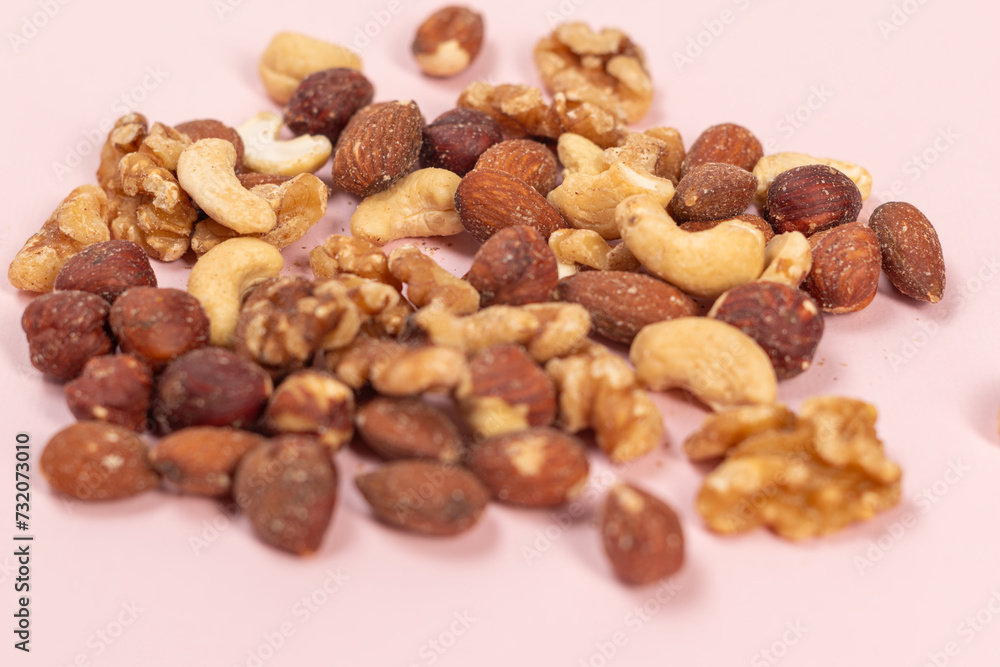 Mix of different nuts on a pink background, close-up of different types of nuts Mix of different nuts on a pink background, close-up of different types of nuts