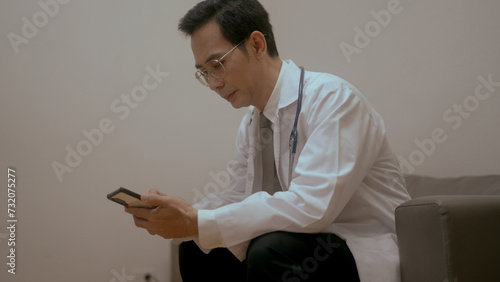 male doctor holding smartphone texting message,