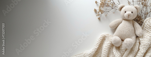 Extra wide banner flatlay image of knit plush stuffed child's toy bear in soft neutral colors with blanket and flowers. Good for product mockup scene creator, text background copy space. Great for you