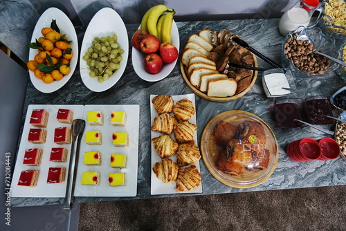 Various types of food are available on the buffet table for breakfast at the hotel, including pastries, cakes, and fruits.