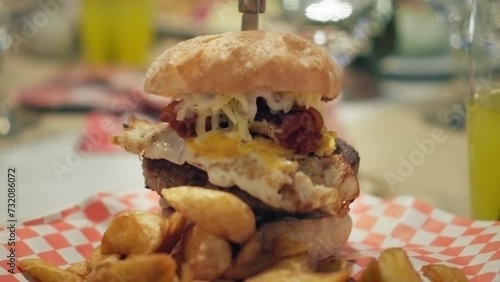 4K shot of a tasty homemade hamburger in a small american restaurant, unhealthy fast food, egg barbecue burger meal, cinematic slow motion video